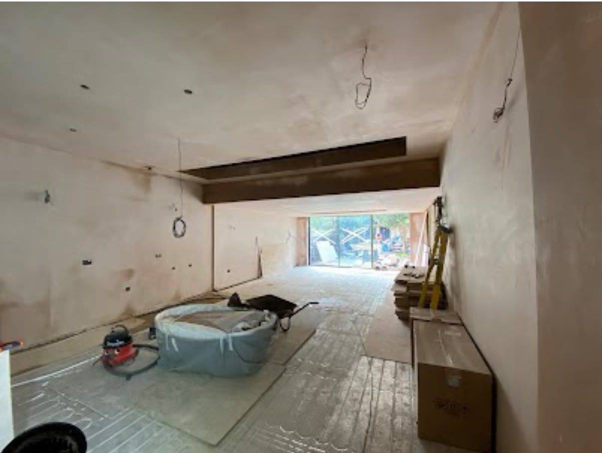 Large open-plan room freshly plastered with exposed beam